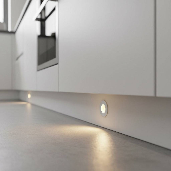 Silver LED kickboard lights installed into a white kitchen plinth.