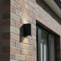 black outdoor up down light installed on a brick wall