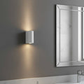 white contemporary sconce for bathroom mounted next to a bathroom mirror
