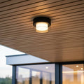 black outdoor ceiling light fixture mounted on a wooden ceiling outdoors