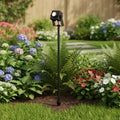 black ground spike light installed in a garden border among flowers