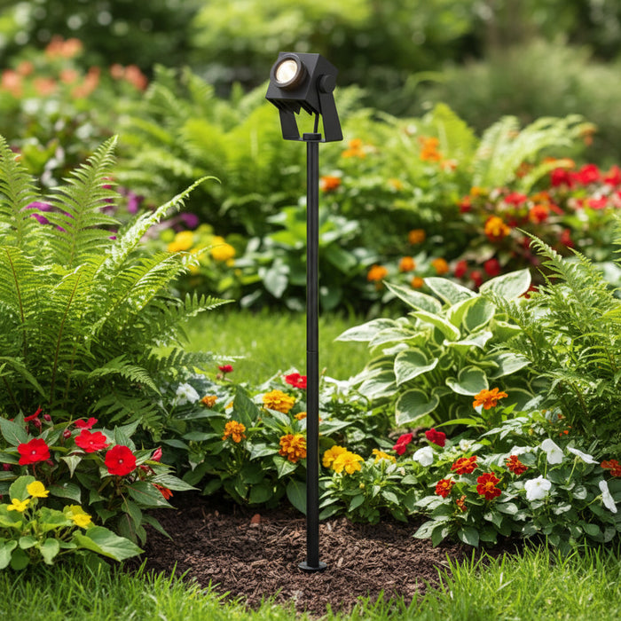 black ground spike light installed in a planted garden border