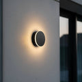 black LED outdoor wall lamp mounted on a concrete wall outside of a modern house