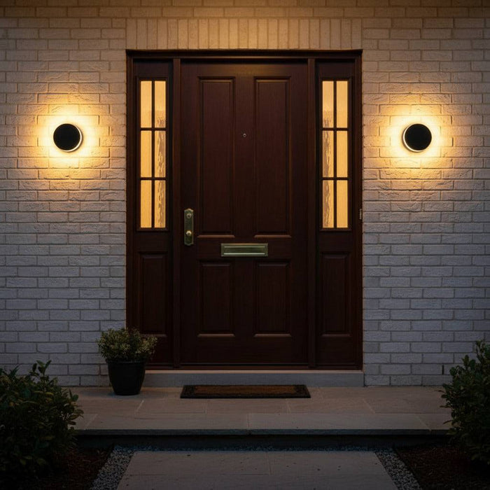 black LED outdoor wall lamp mounted on a brick wall either side of a wooden front door