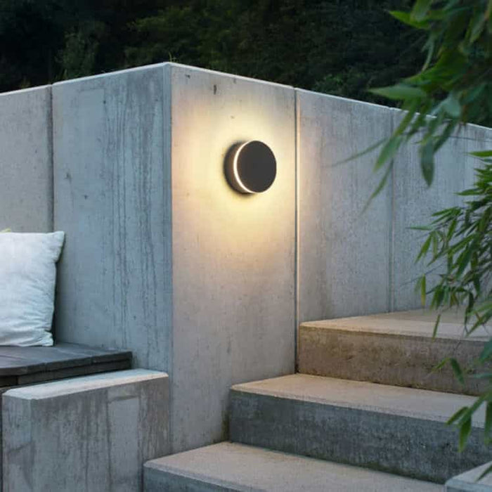 black LED outdoor wall lamp mounted on a concrete wall next to some steps