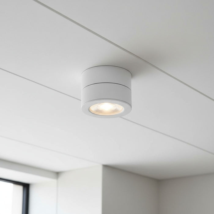 white surface mount adjustable spotlight installed on a white ceiling in a modern house