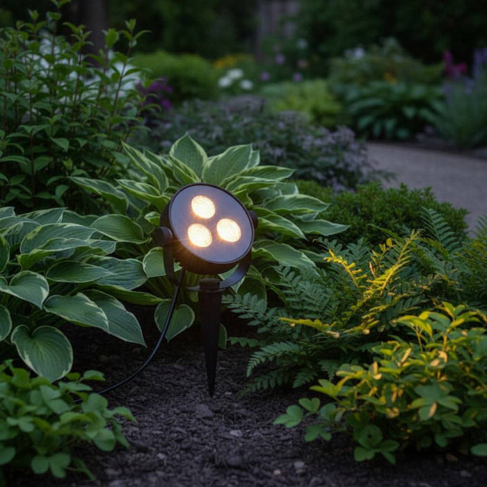 black LED ground spike light installed in a garden border