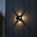 black outside wall light fixture mounted on the wooden exterior wall of a modern house