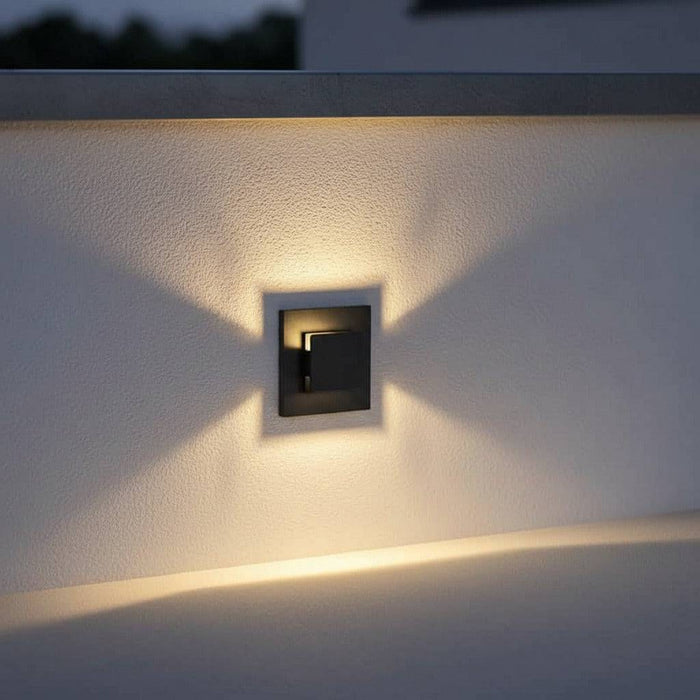 black recessed outdoor wall light mounted at low level on a white outdoor wall