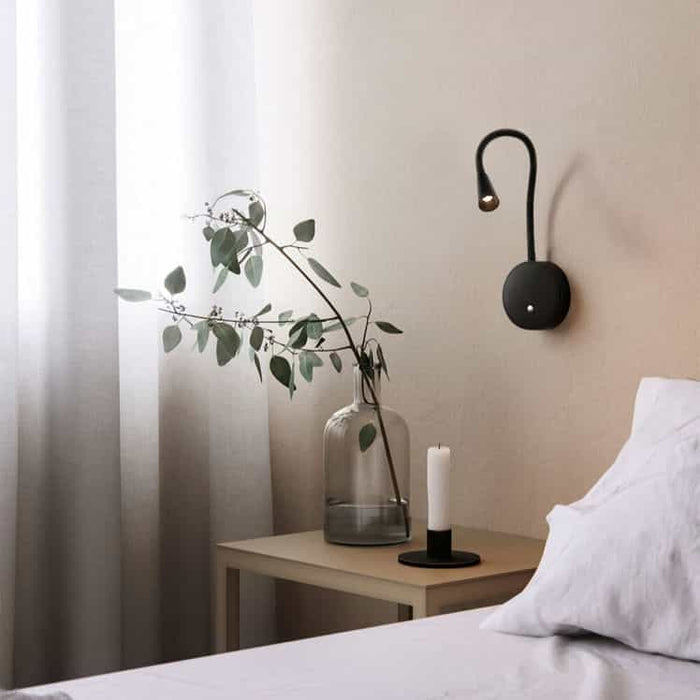 black flexible LED reading light installed next to a bed in a modern bedroom