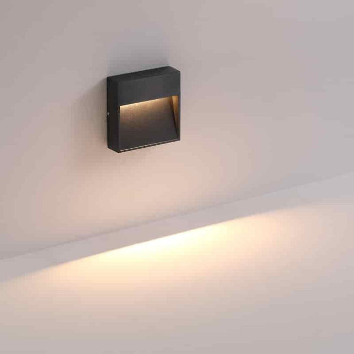 black outdoor low level wall light shown mounted on a white wall