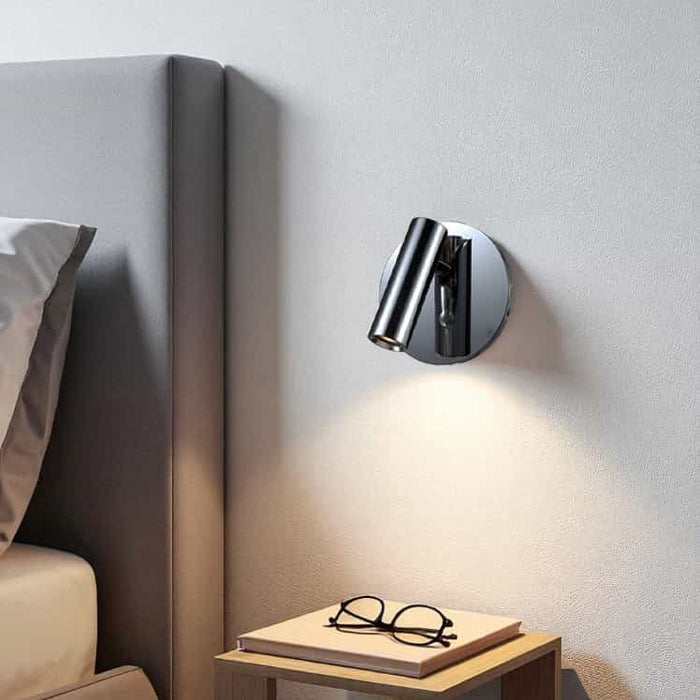 polished chrome bed reading lamp mounted on the wall next to a bed in a minimailst bedroom