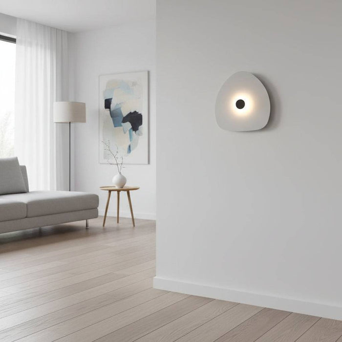 Modern internal wall light with a white finish and a black central halo on a wall within  a modern lounge