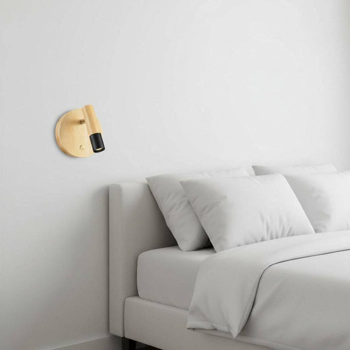black adjustable wooden reading lamp fitted on the wall next to the bed in a bedroom