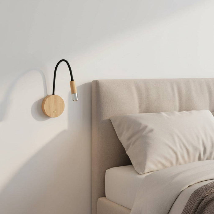 beech wood flexible wooden reading light mounted on the wall next to the bed in a minimalist bedroom