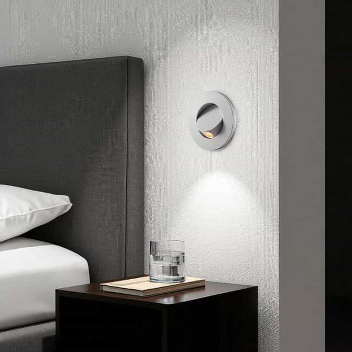 white recessed bedside reading light mounted on the wall next to a bed above a bedside table