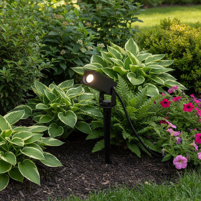 black spike light fixture mounted on the ground in a modern garden