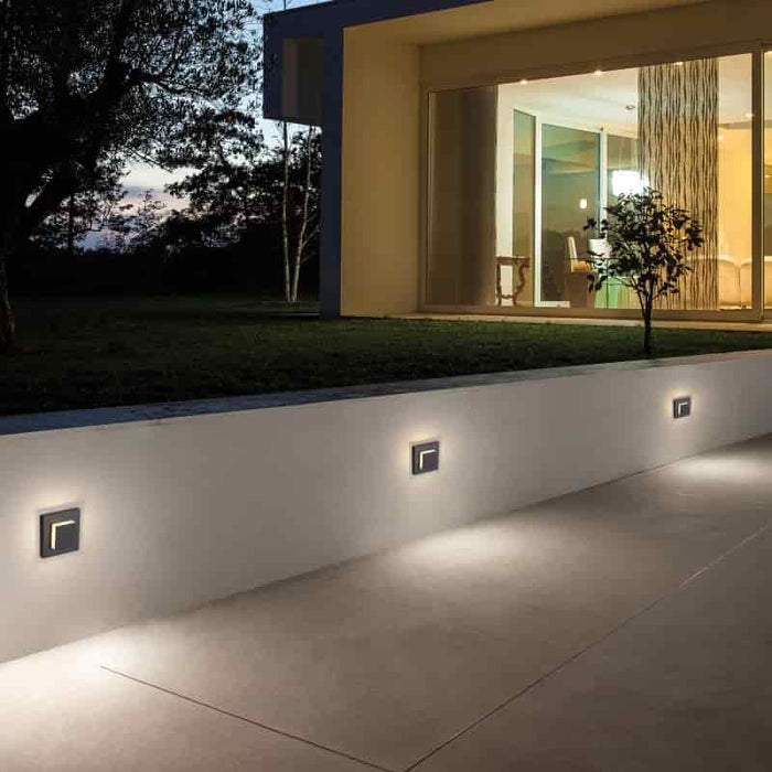 black flush outdoor wall light mounted in a row at low level along an exterior wall