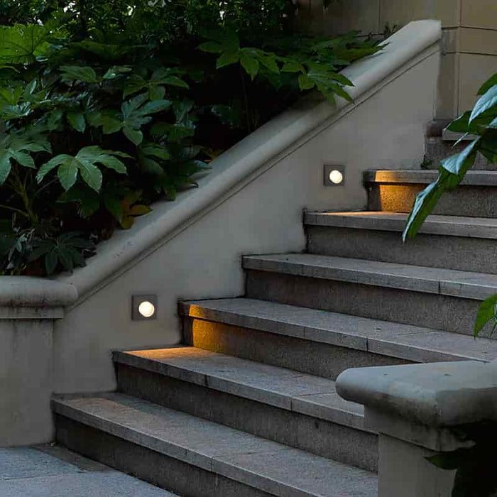 black outdoor step light mounted in the wall alongside some stone steps