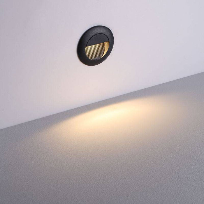black outdoor stair light mounted at low level on a white wall