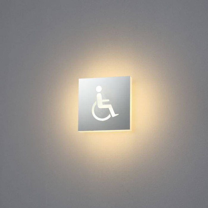 LED disabled toilet sign mounted on a white wall
