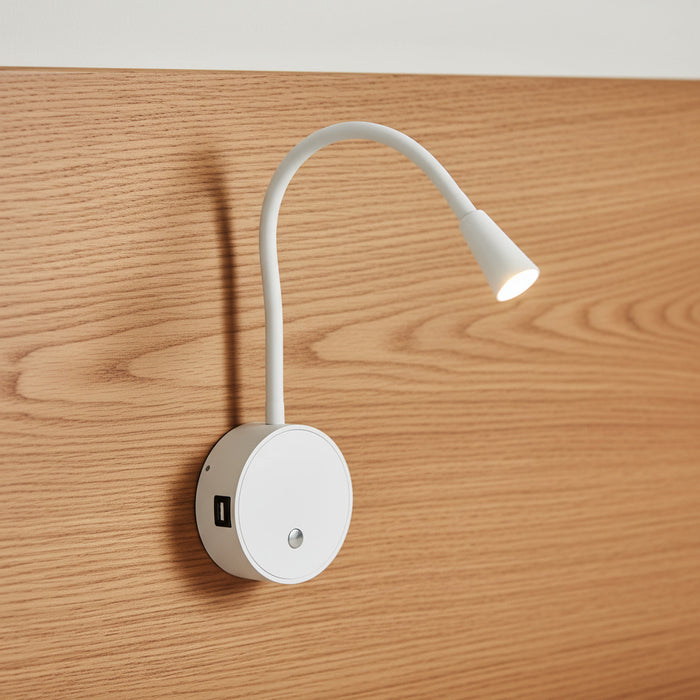 white flexible LED reading lamp mounted on a wooden bed headboard