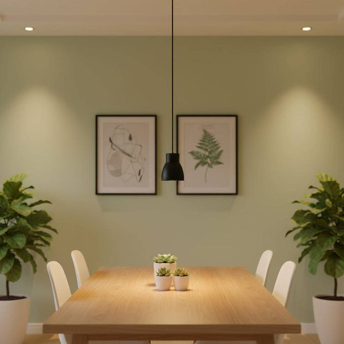 Black LED pendant lamp above a pine and white dining table against a pale green wall with pictures