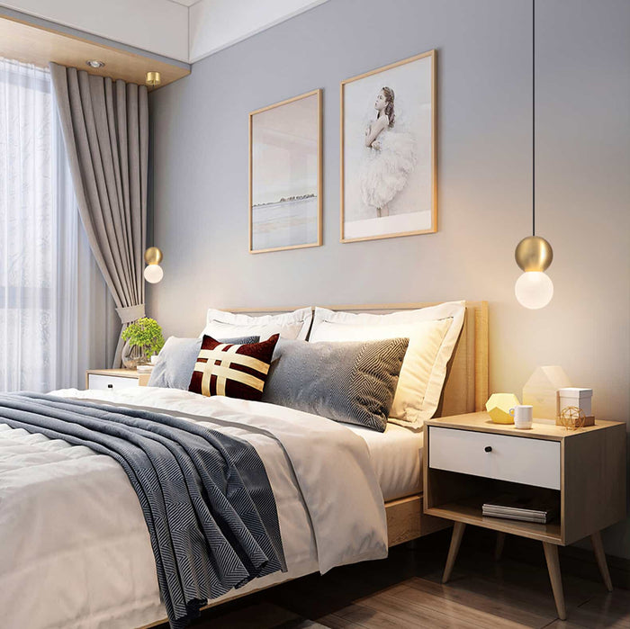 Gold round LED pendant light either side of a bed in a modern bedroom
