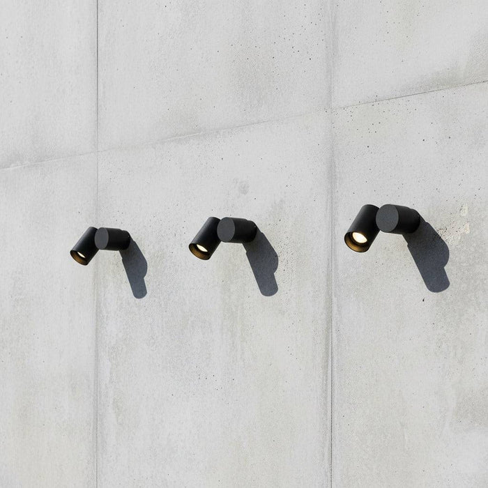 black exterior spotlight wall light showing 3 lights mounted on a concrete wall in a row