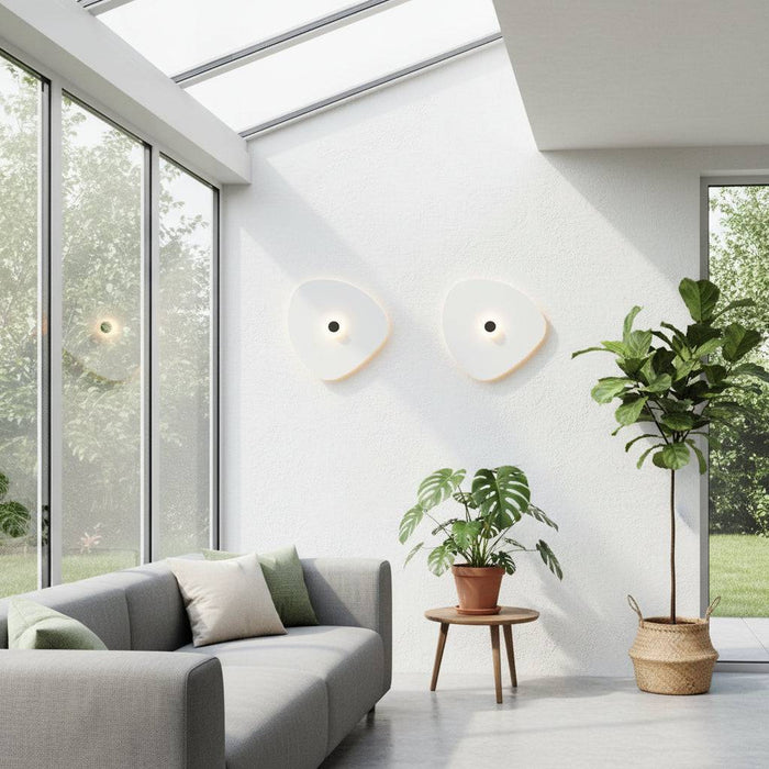 White indoor decorative wall sconce with a black centre where the light emits situated in a conservatory