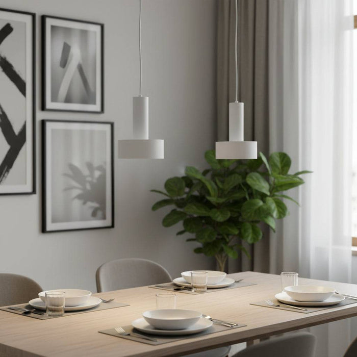 Modern white pendant lights over a dining room table with plants and pictures