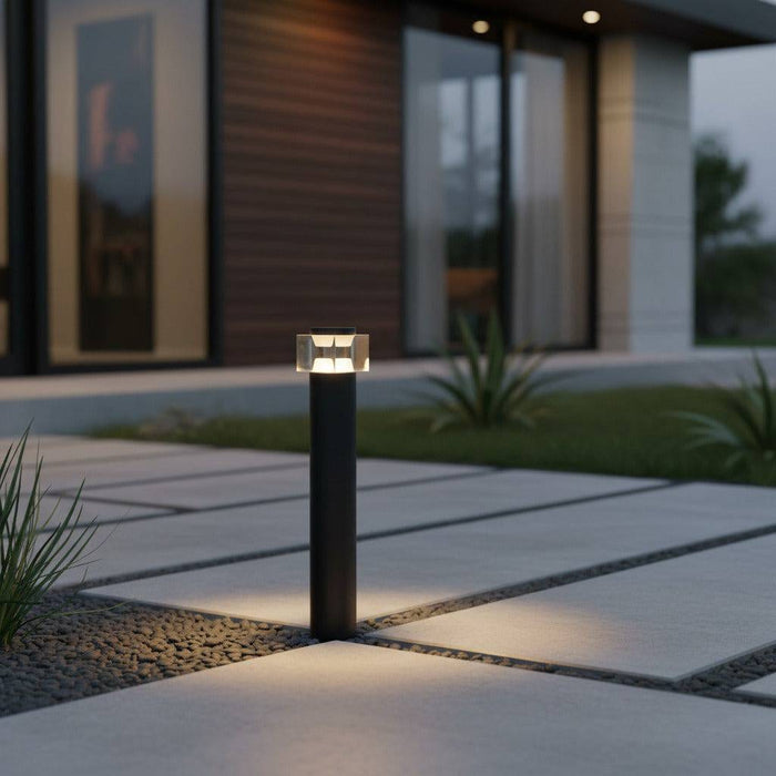 black exterior bollard light installed alongside the pathway of a modern house