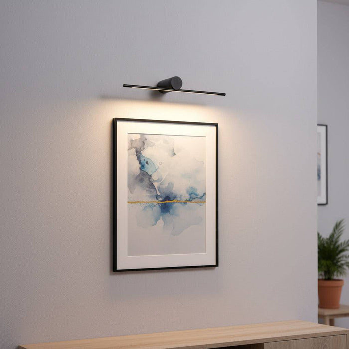 black picture light mounted over artwork on the wall