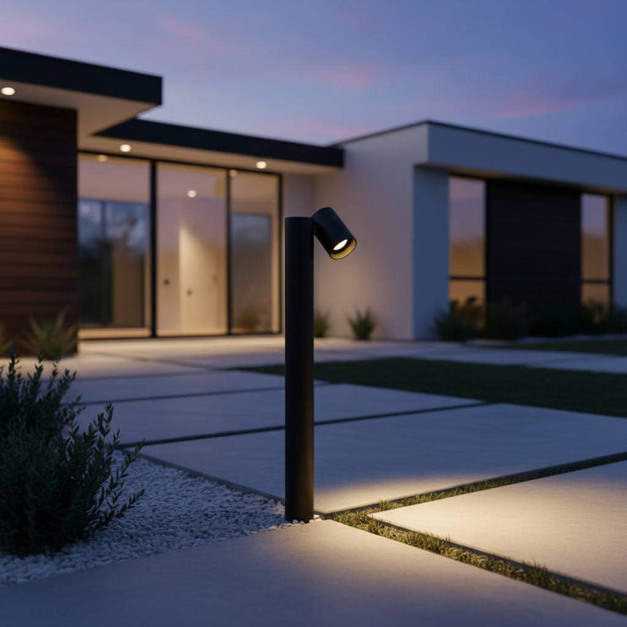 Black adjustable bollard light on large pathway leading to a modern house