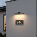 black sign wall light mounted over a house number on the wall of a modern house
