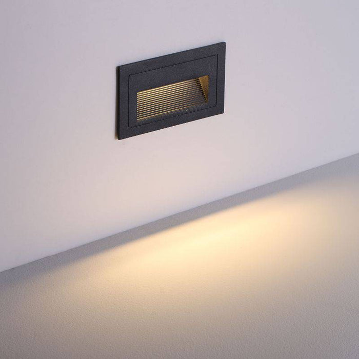 black low level external wall light mounted on a white wall