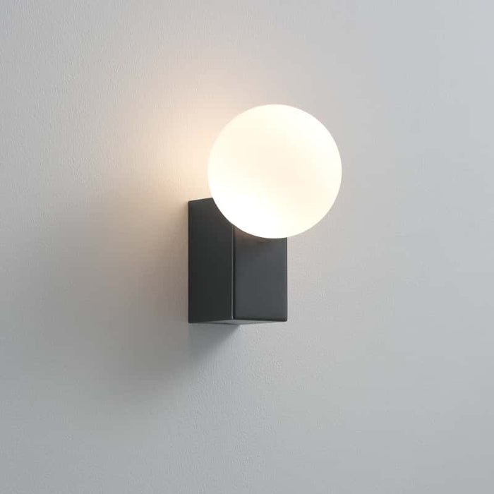 black outdoor wall globe light mounted on a white wall