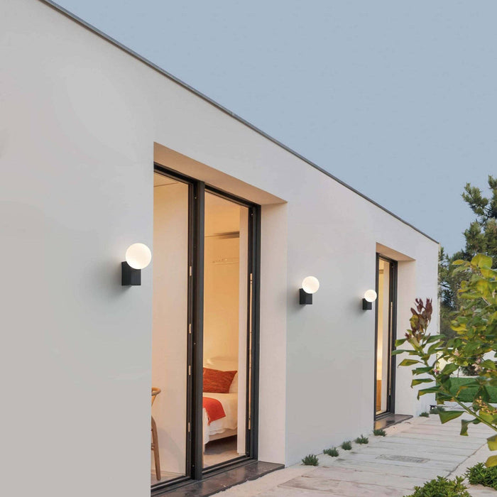 black outdoor wall globe light 3 lights mounted on the white wall of a modern home