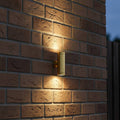 brass up down outdoor wall light mounted on a brick wall of a home