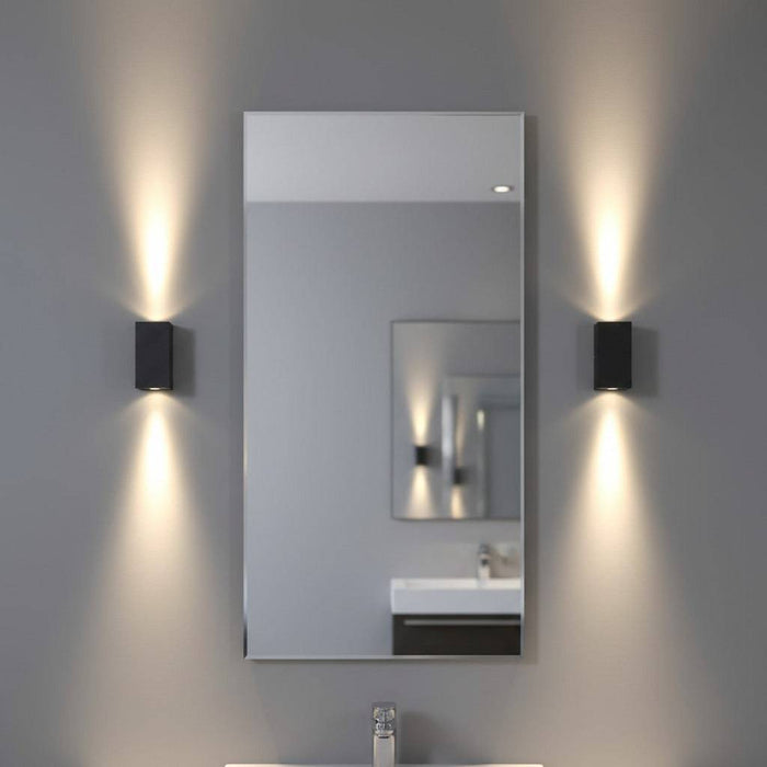 modern black bathroom sconce mounted either side of a mirror in a bathroom