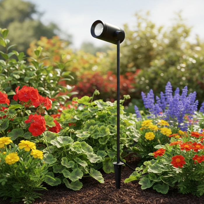 black outdoor LED spike light in a planted garden