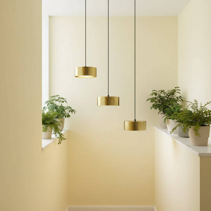 Gold pendant lights in a stairwell with plants and with pale yellow walls