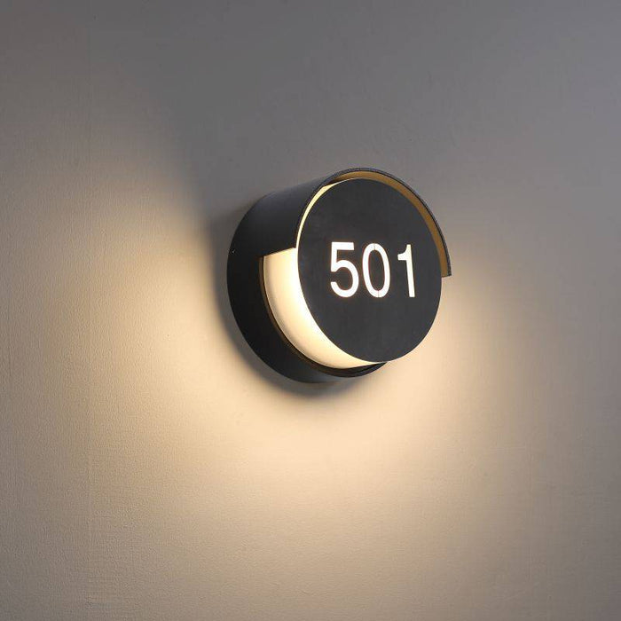 black illuminated door number mounted on a white wall