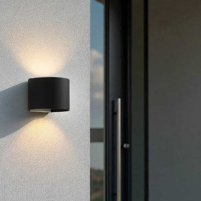 black up down outside light fitted on a white textured wall next to the entrance door of a modern home