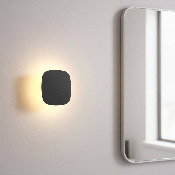 black vanity wall light mounted next to a bathroom mirror on the wall