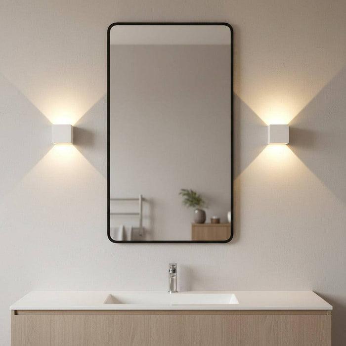 white modern bathroom wall light mounted either side of a bathroom mirror