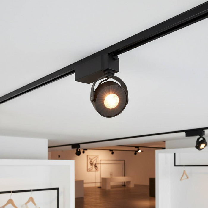 black slim track light fitting mounted on the ceiling in an art gallery