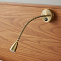 antique flexible bedside reading light mounted on a wooden headboard