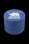 Angled top-down view of a blue Cali Crusher Homegrown 4-Part Grinder showing its stacked tiers and white bear logo on a black background.