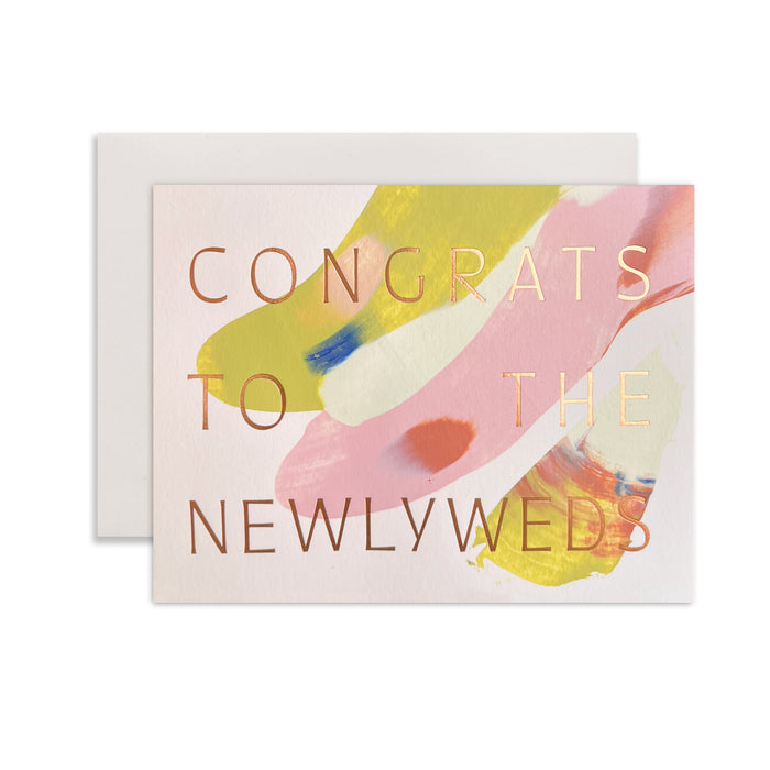 Congrats To The Newlyweds handmade purple artisanal greeting card with, pink and yellow paint swirls and an envelope on a white background.